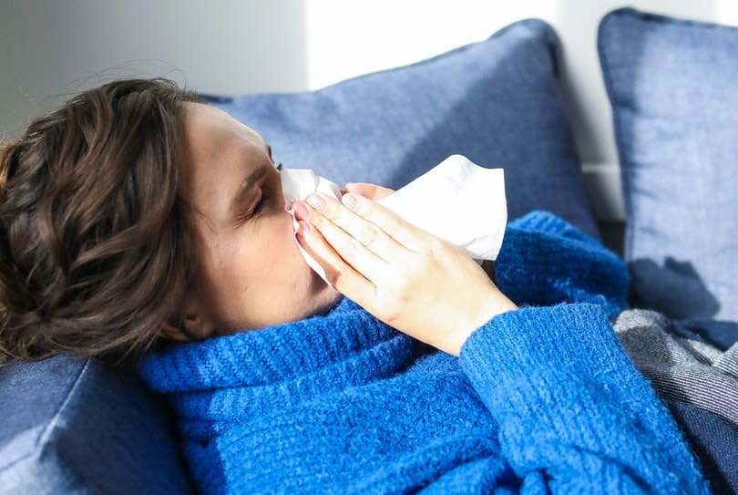 woman in blue sweater having allergy