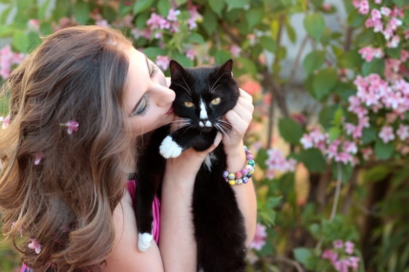 woman kissing black cat