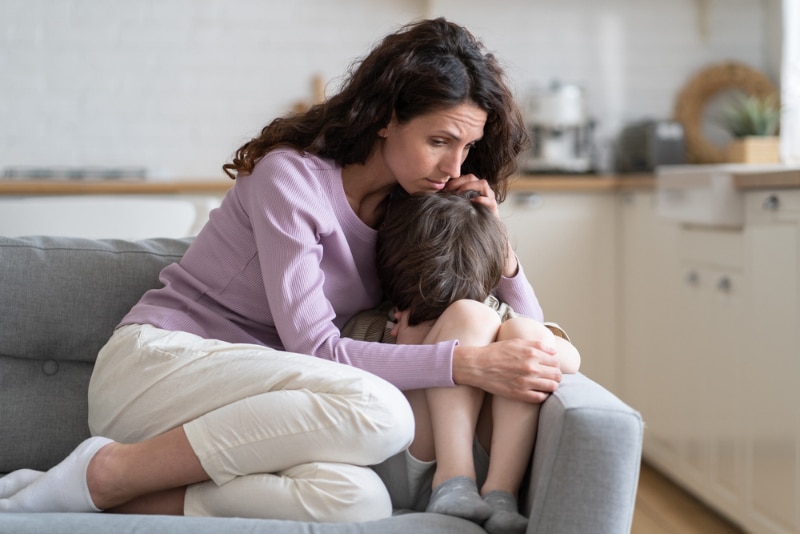 Caring mother consoling kid with tender embraces