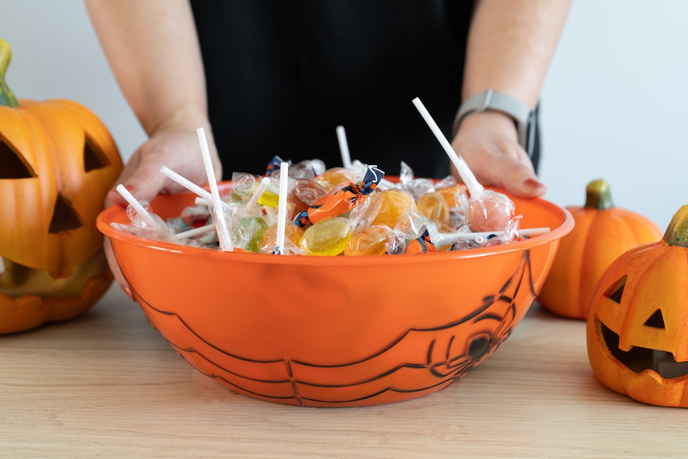 Woman holding a Halloween candy bowl filled with sweets for trick-or-treating