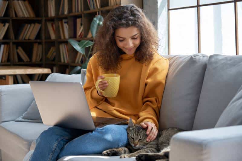 a young girl using her laptop with her pet cat