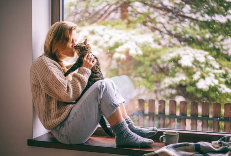 cat owner with her cat near window|