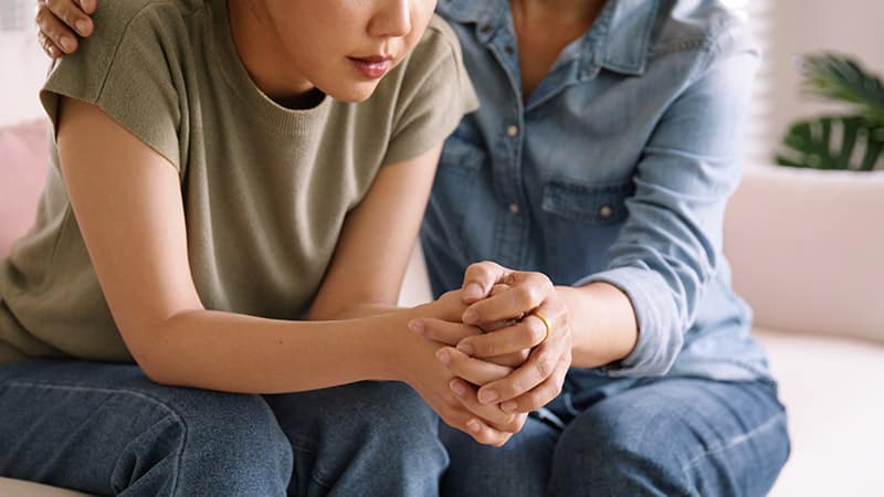 two woman holding hands while sitting