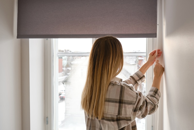woman opening or closing the window blinds