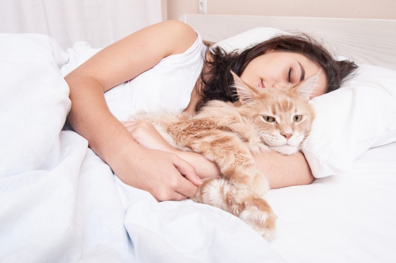 woman sleeping in bed with her cat
