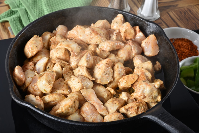 Frying seasoned cubed chicken breasts in a cast iron skillet