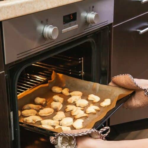 Woman opens the oven to cool off the pastry
