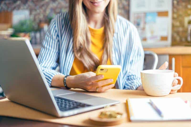 woman looking at her phone while having a coffee