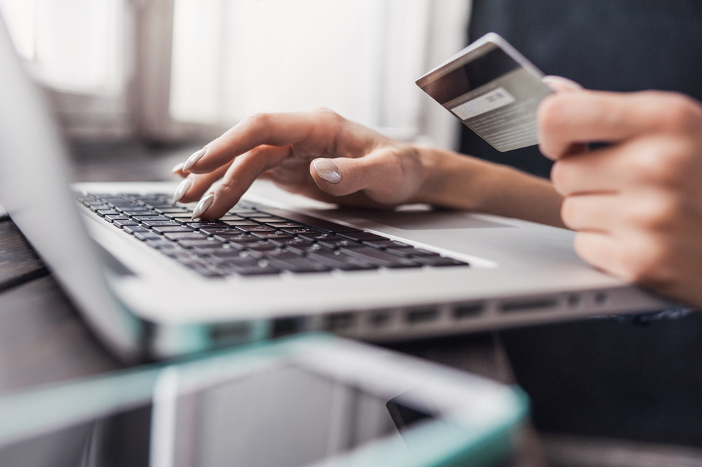 Hand holding credit card and using laptop