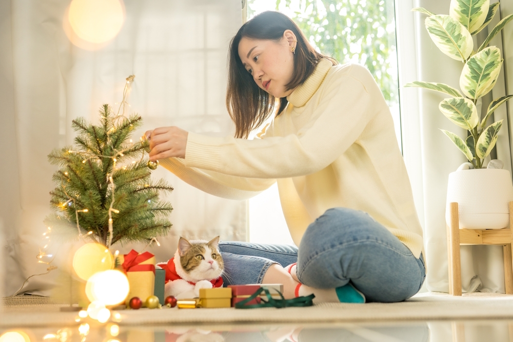 woman-decorate-christmas-tree-with-her-cat